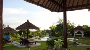 A tropical resort with thatched-roof structures, lounge chairs, and a central water feature. - Typical Balinese villa with beautifully landscaped swimming pool (Buleleng)