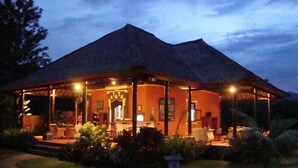 A building with a thatched roof, a covered outdoor seating area, and a well-maintained garden. - Typical Balinese villa with beautifully landscaped swimming pool (Buleleng)