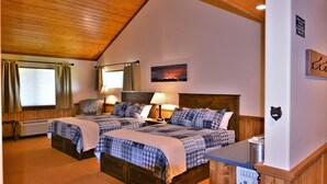 A room with two beds, wooden ceiling, a painting of a mountain, and a bear-shaped wall decoration. - McAllister Inn & Lodging (McAllister)