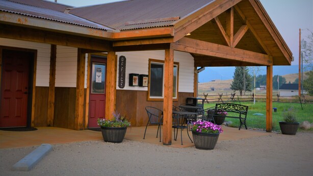 A rustic building with a covered patio, wooden beams, and outdoor seating. - McAllister Inn & Lodging (McAllister)