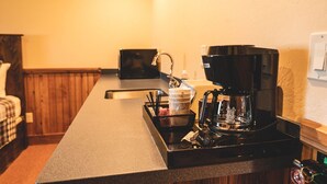 A kitchenette with a coffee maker, a sink, and a countertop. - McAllister Inn & Lodging (McAllister)
