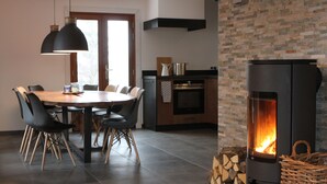 A modern kitchen with a large dining table, black chairs, a stove, and a brick wall.