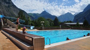 A swimming pool with a wooden deck, a slide, and a sign indicating a depth of 2 meters.