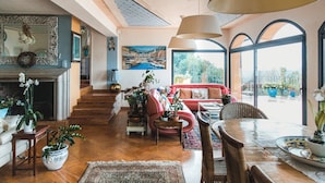 A spacious living room with a fireplace, a red sofa, and a dining area with a table and chairs.