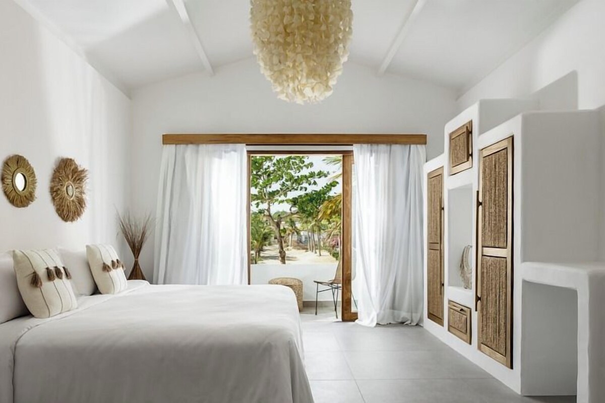 Une chambre à coucher avec un lit, des rideaux, une vue sur l’extérieur et un luminaire au plafond.