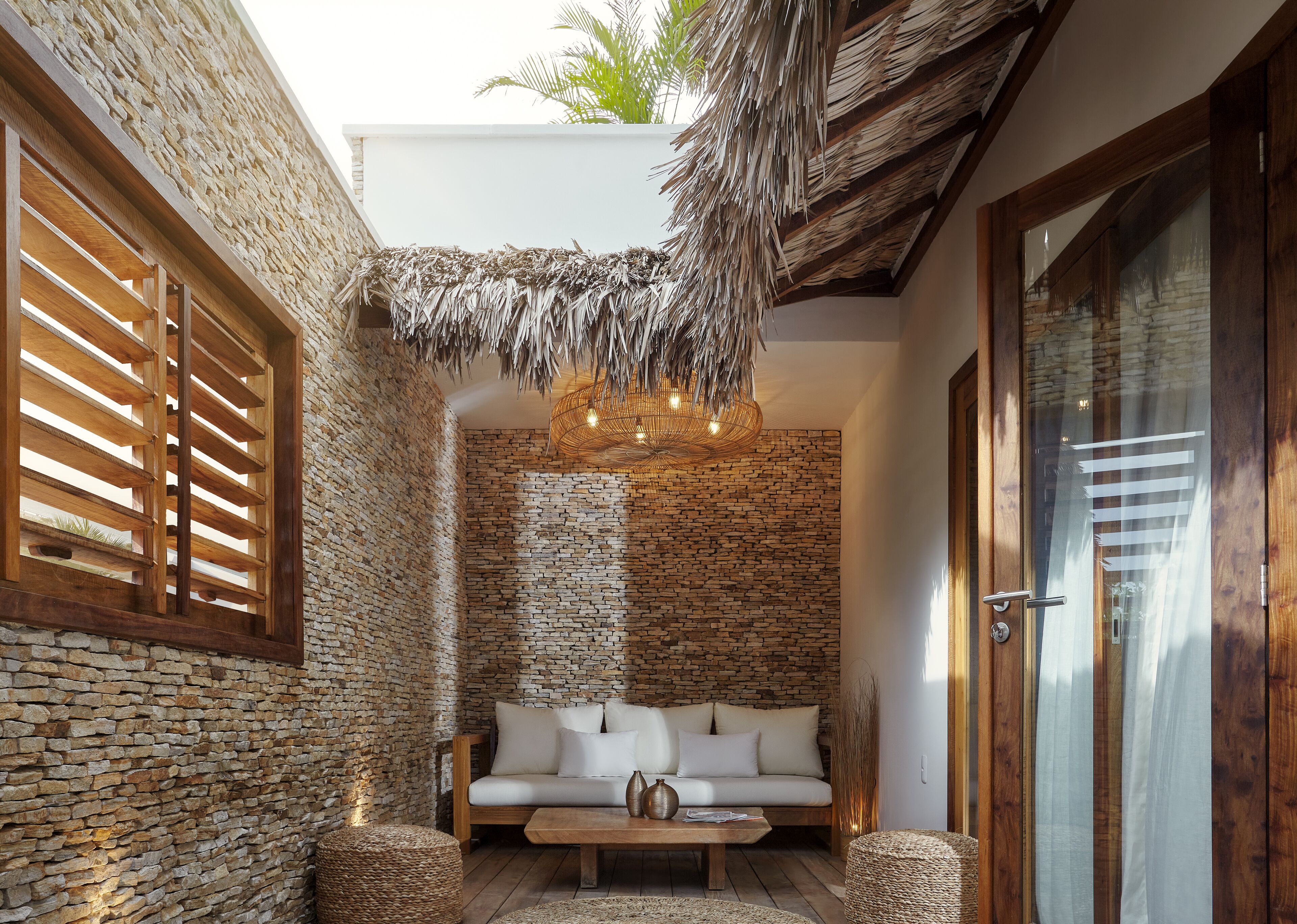 Una habitación acogedora con pared de piedra, un banco de madera y techo de paja.