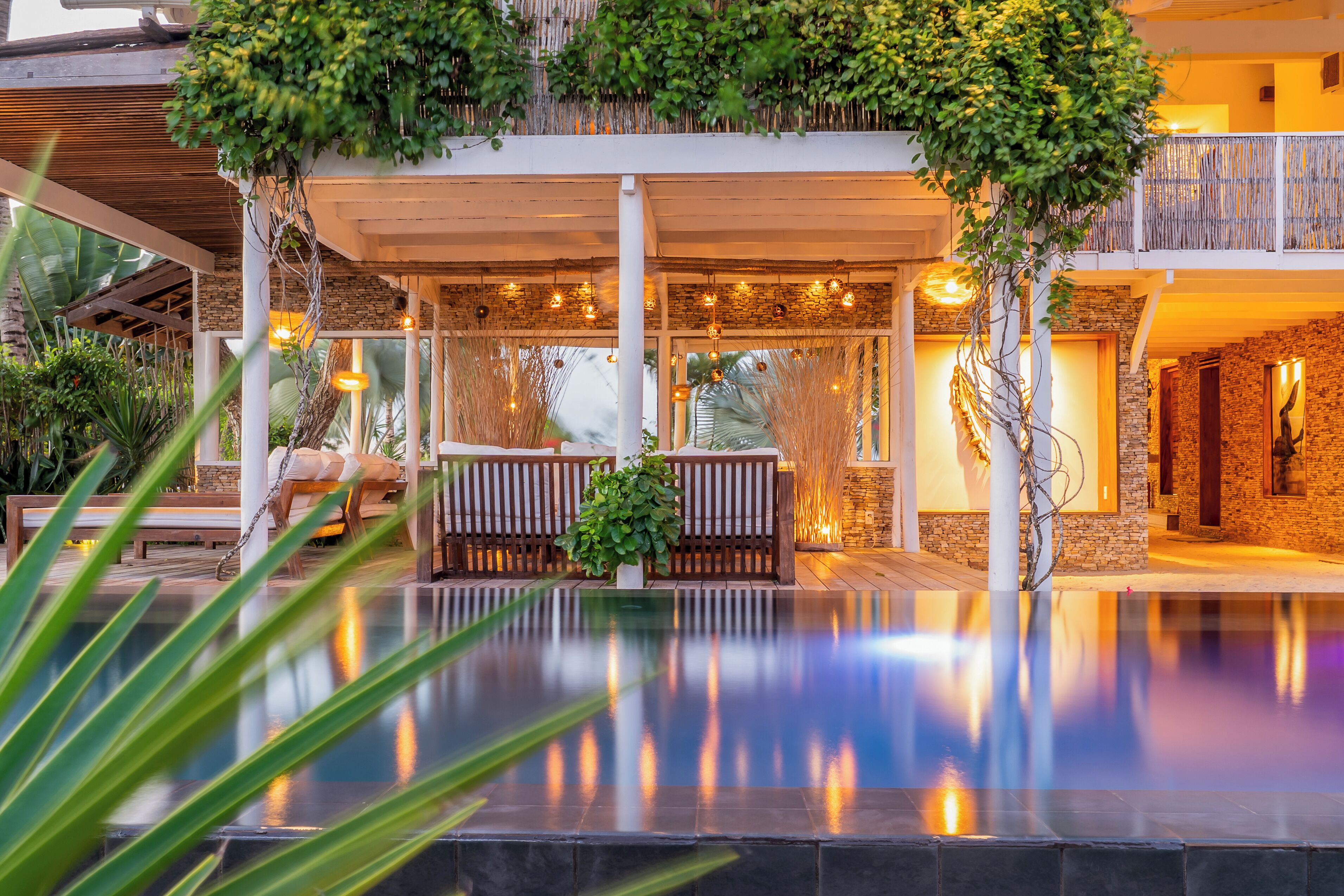 A pool area with a wooden deck, lounge chairs, and a stone wall.