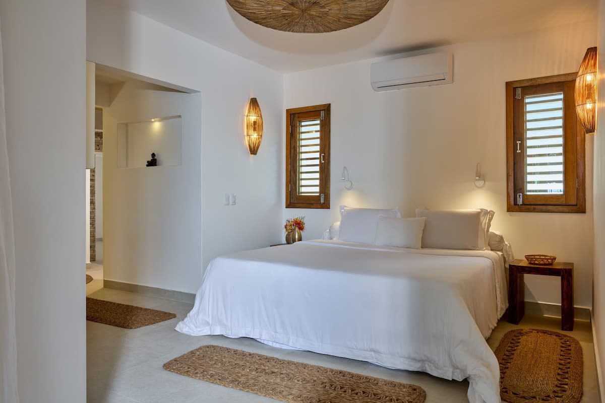 A bedroom with a large bed, a wooden door, and a small table.