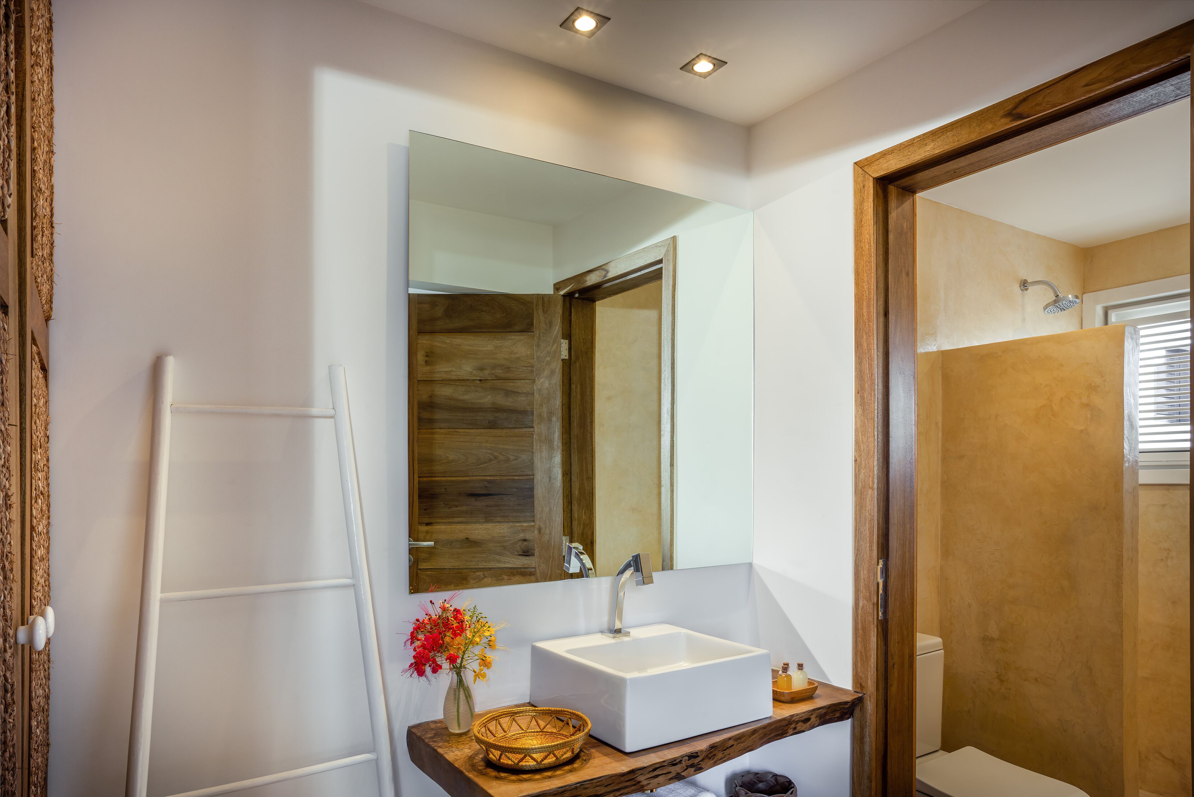 A modern bathroom with a white sink, wooden vanity, and a large mirror.