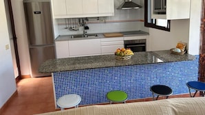 A modern kitchen with white cabinets, a stainless steel refrigerator, a granite countertop, and a blue-tiled backsplash. - A house, a villa, a charm, comfortable interior and wonderful exterior. (Puerto Rico)