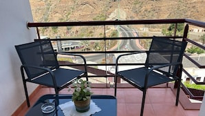A balcony with two black chairs and a small table with a plant and a glass. - A house, a villa, a charm, comfortable interior and wonderful exterior. (Puerto Rico)