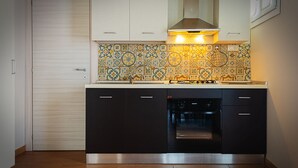 A modern kitchen with a built-in oven, black cabinets, and a patterned backsplash. - The house of Bice - accommodation 2 (Siracusa)