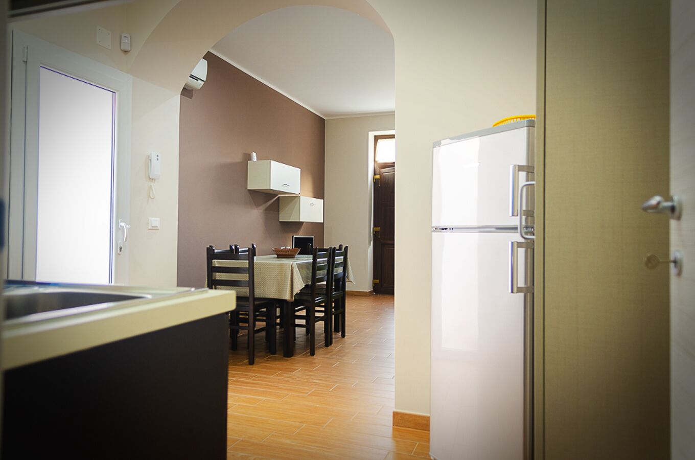 A kitchen with a dining table, chairs, and a refrigerator.