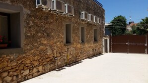 A stone building with air conditioning units, a gated entrance, and a clear sky. - The house of Bice - accommodation 2 (Siracusa)