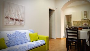 A living room with a green sofa and a dining area with a table and chairs. - The house of Bice - accommodation 2 (Siracusa)