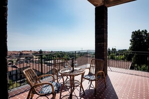 A balcony with wicker furniture, a table, and a view of a town. - A Villa Offering Comfort and Relaxation Between Mount Etna and the Sea (Zafferana Etnea)