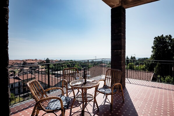 A balcony with wicker furniture, a table, and a view of a town.