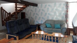 A living room with a wooden staircase, two sofas, a wooden coffee table, and patterned wallpaper.