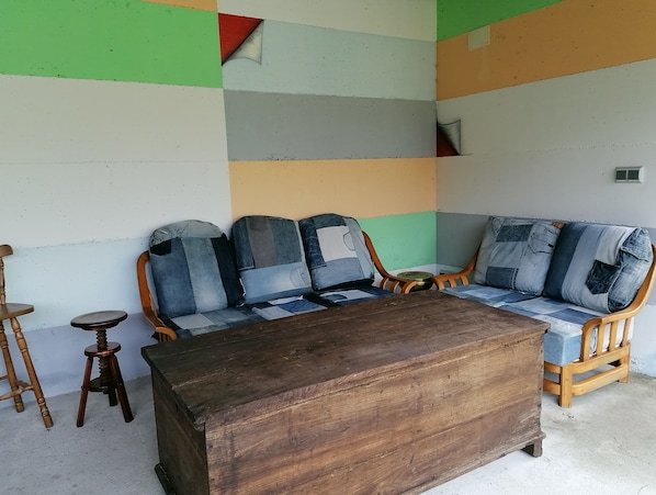 A room with a wooden sofa with denim cushions, a wooden coffee table, and a wooden chair.