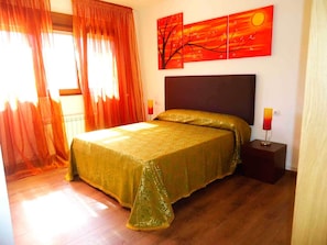 Une chambre à coucher avec un grand lit, une table de chevet, une lampe et un mur orné de trois tableaux.