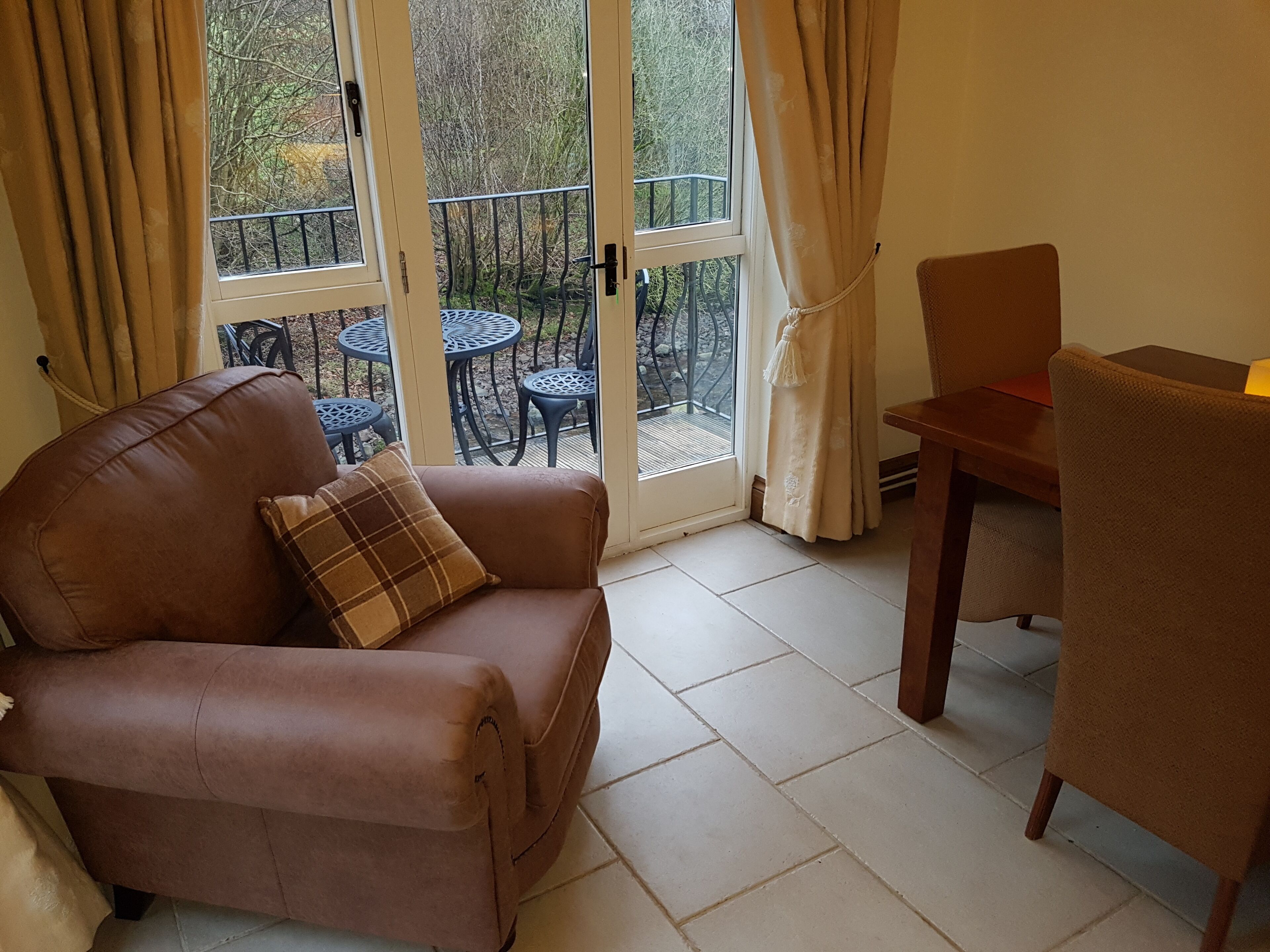 Une pièce chaleureuse avec un canapé en cuir marron, un coussin à carreaux, une table en bois et une chaise.