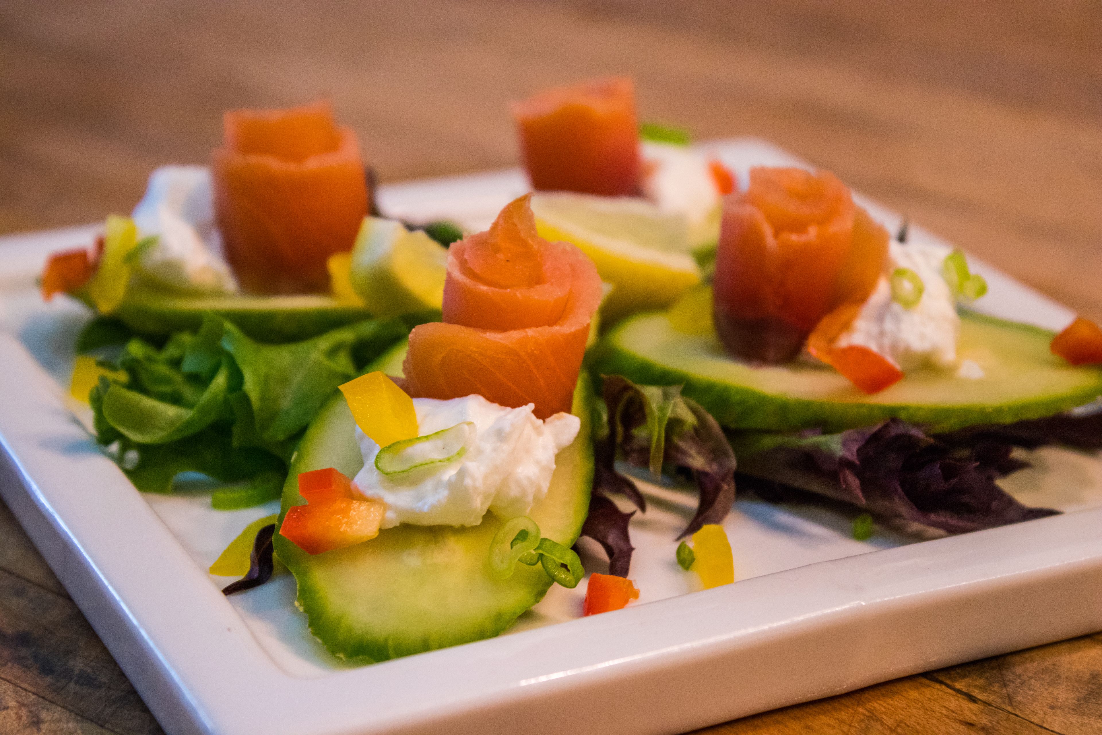 A plate of food with salmon, avocado, and vegetables.