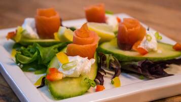 A plate of food with salmon, avocado, and vegetables.