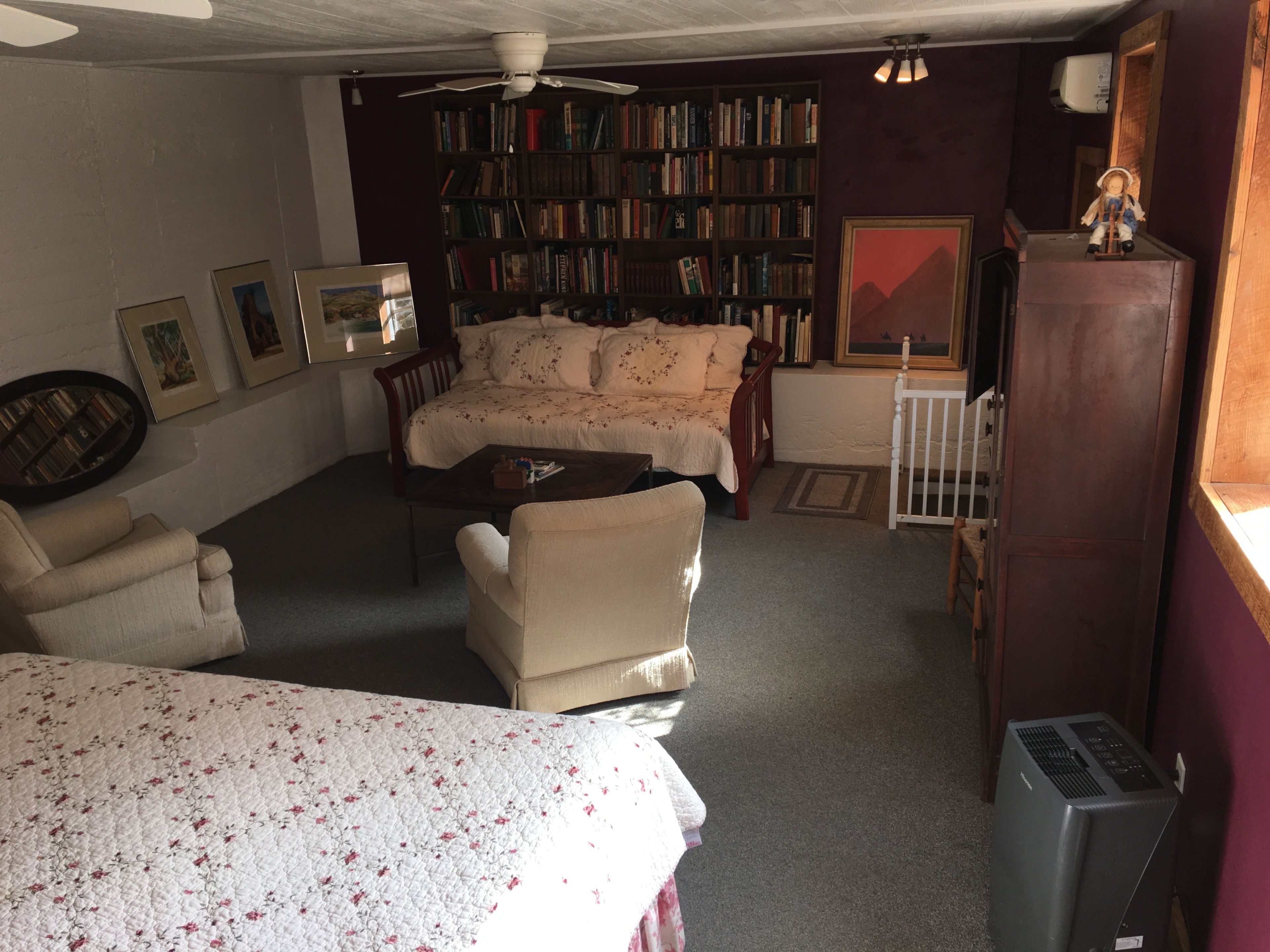A cozy living room with a sofa, armchairs, a coffee table, a bookshelf, and a small table with a figurine.