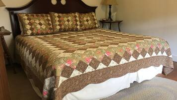 A bed with a quilt, a nightstand, a lamp, and a rug.