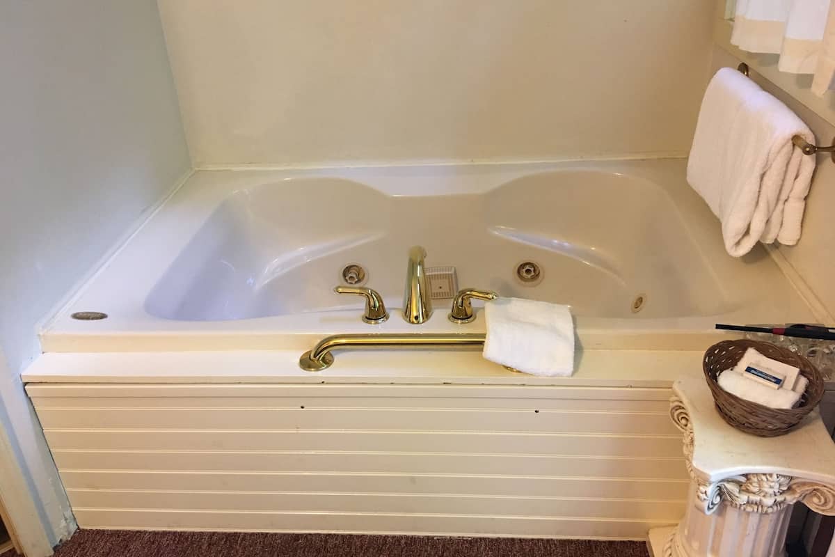 Un baño con una bañera, un perchero para toallas y una mesita con una cesta.