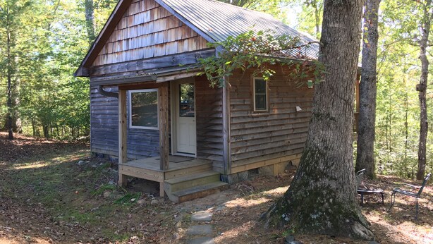A small wooden cabin with a porch, a door, and a window. - River House Inn (Grassy Creek)