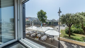 Uitzicht vanuit een hotelkamer op een straat met terrasjes en een lantaarnpaal.