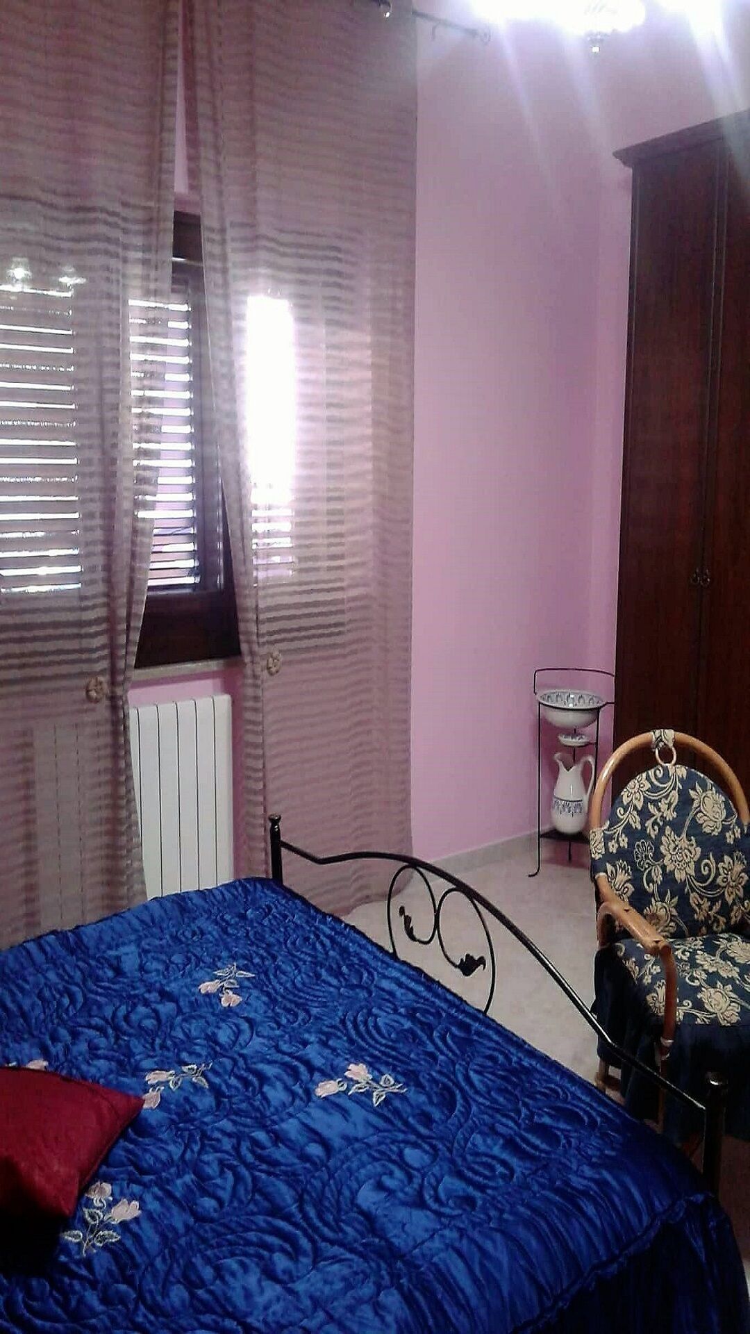 Une chambre à coucher avec un lit, une chaise, un radiateur et une armoire.
