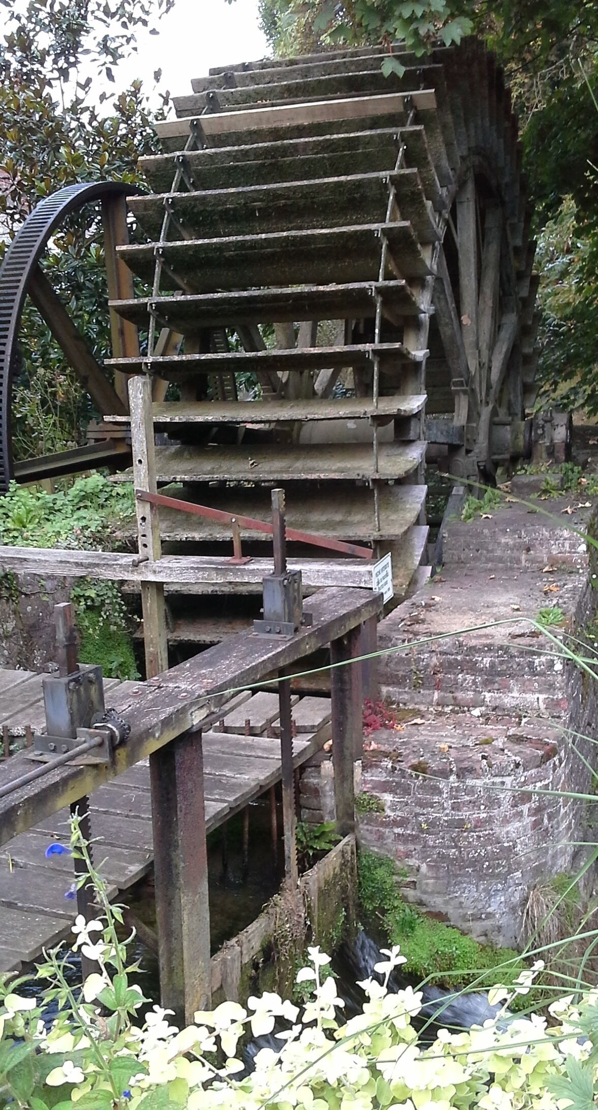 A large, rustic water wheel structure with a wooden platform in front.