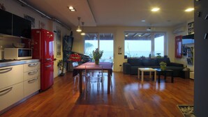 A modern kitchen with a red refrigerator, a dining table with chairs, and a view of the sea through large windows. - design villa on the sea with a splendid view of the Gulf of Syracuse (Siracusa)
