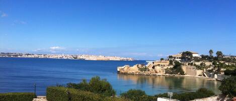 A coastal view with a clear sky, a body of water, and a distant cityscape.