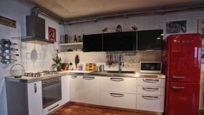 A modern kitchen with white cabinets, a stainless steel oven, a red refrigerator, and a black microwave. - design villa on the sea with a splendid view of the Gulf of Syracuse (Siracusa)