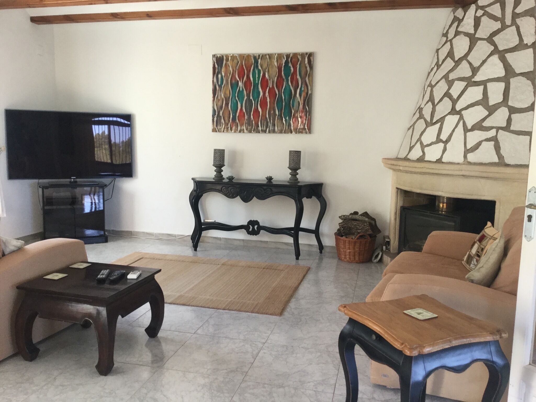 A living room with a television, two sofas, a coffee table, a fireplace, and a decorative wall piece.