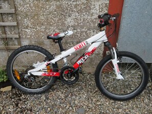 Un vélo de montagne blanc, agrémenté de touches rouges et noires, est garé sur un chemin de gravier.