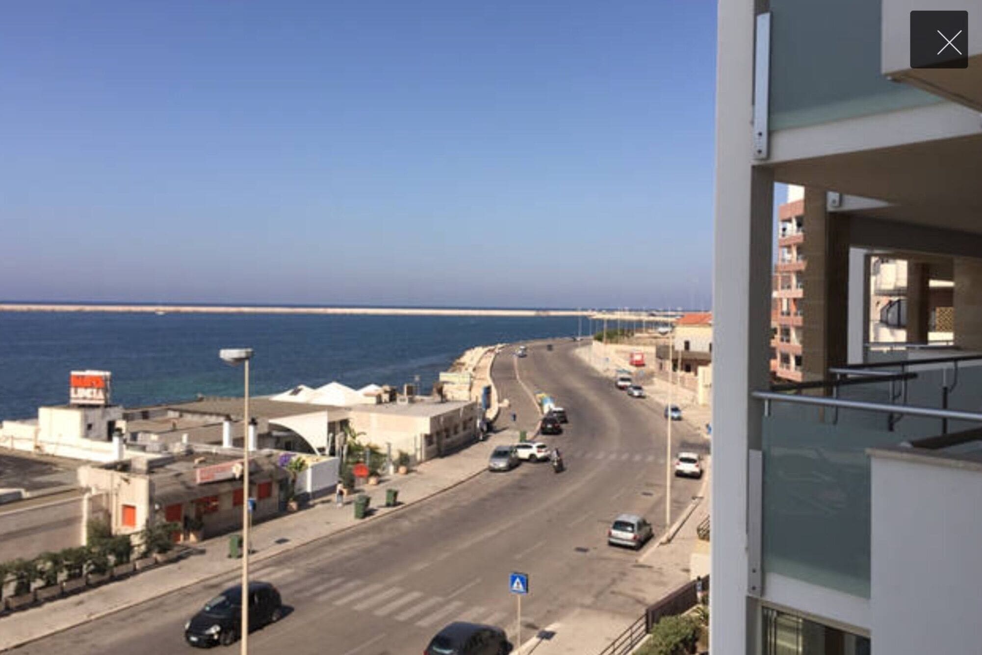 A coastal road with buildings and a clear view of the sea.