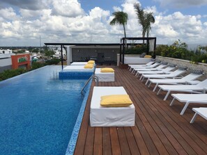 An infinity pool with lounge chairs and a seating area with cushions. - Menesse, The City In Playa Del Carmen, Quintana Roo (Playa del Carmen)