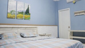 Ein Schlafzimmer mit Bett, Nachttisch, Kommode und Wandklimaanlage.