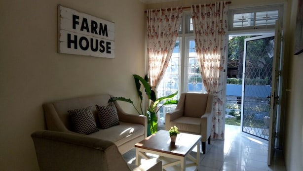 Ein Wohnzimmer mit einer Couch, Sesseln, einem Couchtisch und einem Schild mit der Aufschrift "FARM HOUSE".