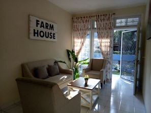 A living room with a sofa, armchairs, a coffee table, and a sign that reads "FARM HOUSE".
