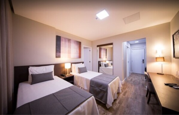 Habitación de hotel con dos camas, un escritorio y un comedor.