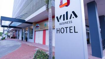 Placa do Vila Business Hotel, com um edifício moderno ao fundo.