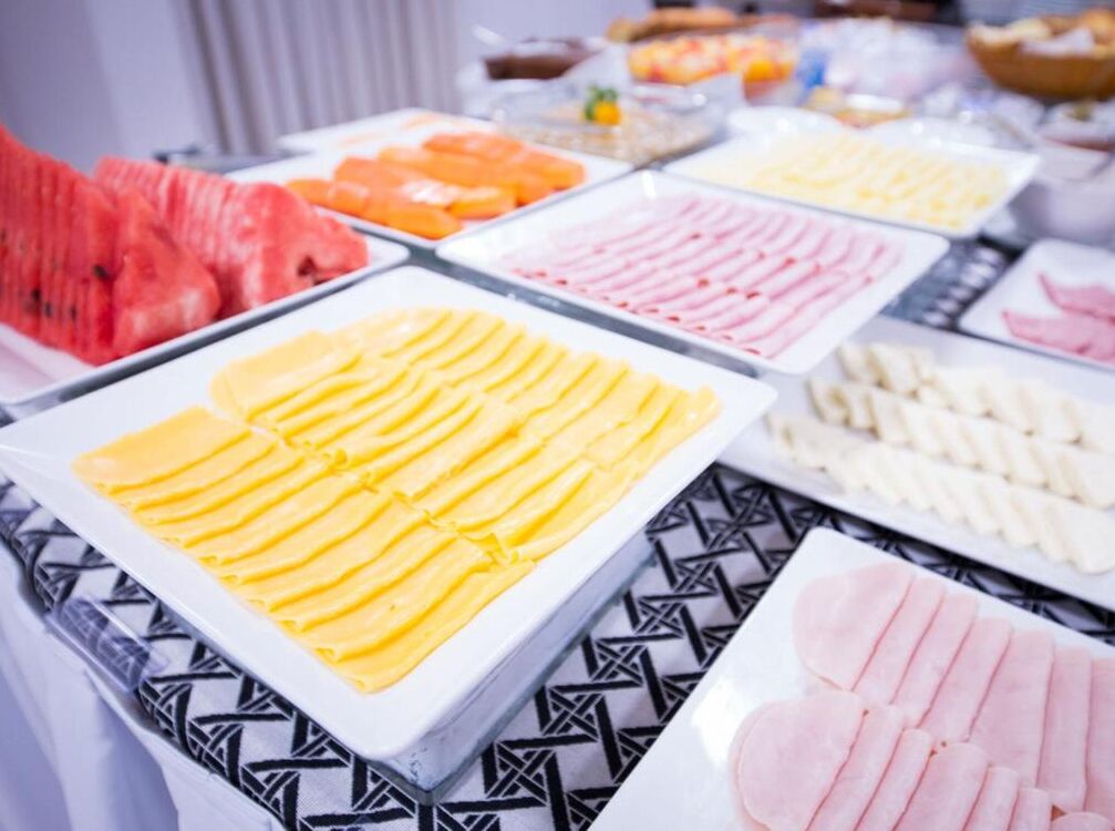 A buffet with various food items including sliced fruits and meats.