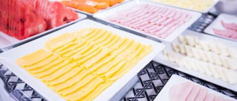 A buffet with various food items including sliced fruits and meats.