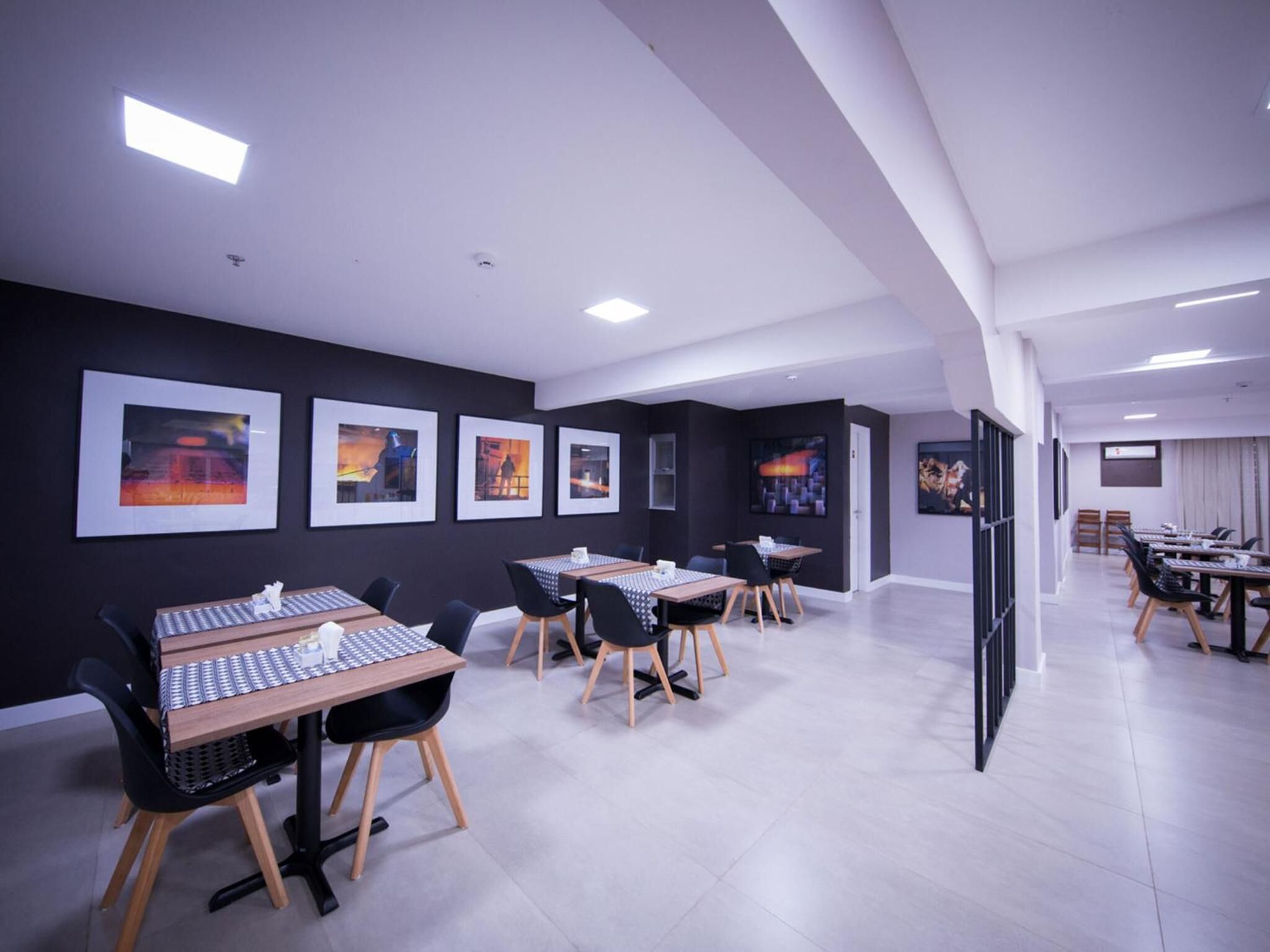 A modern conference room with tables and chairs, framed artwork on the walls, and a clean, minimalist design.