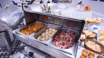 Ein Buffet mit verschiedenen Speisen, darunter Würstchen, Gebäck und Brot.